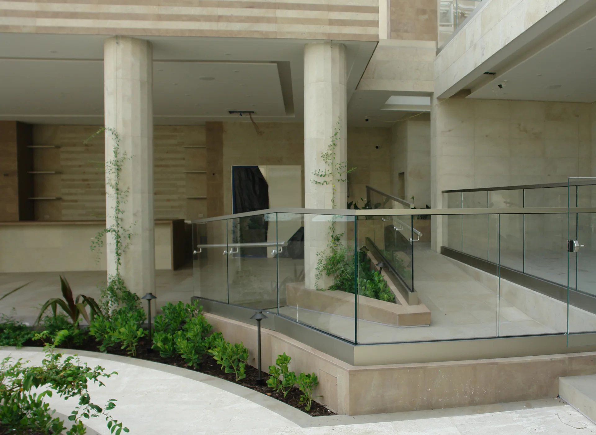 Patio con travertino, barandillas de cristal y vegetación