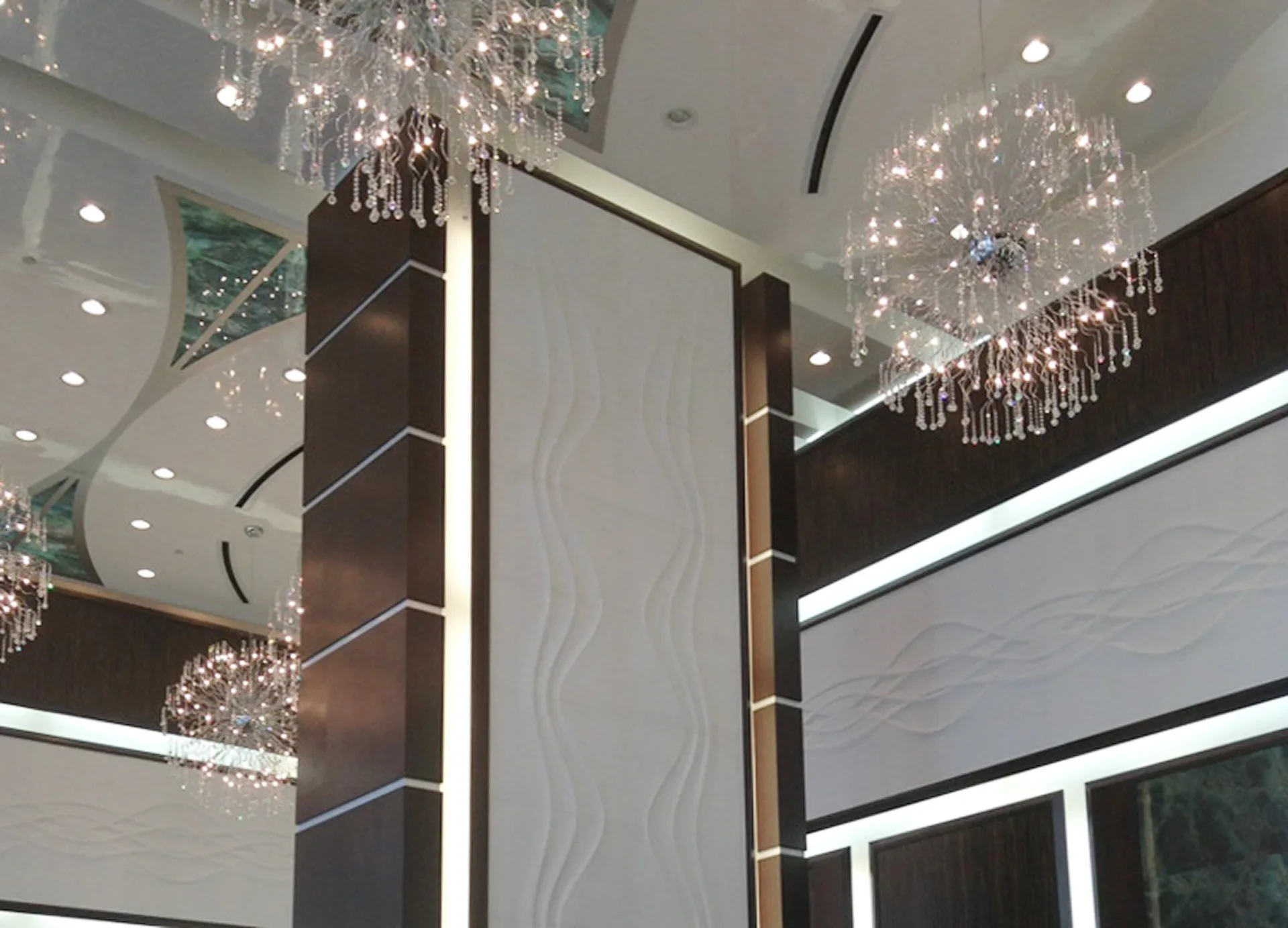 Lobby a doble altura con lámparas de cristal y paneles de mármol ondulado