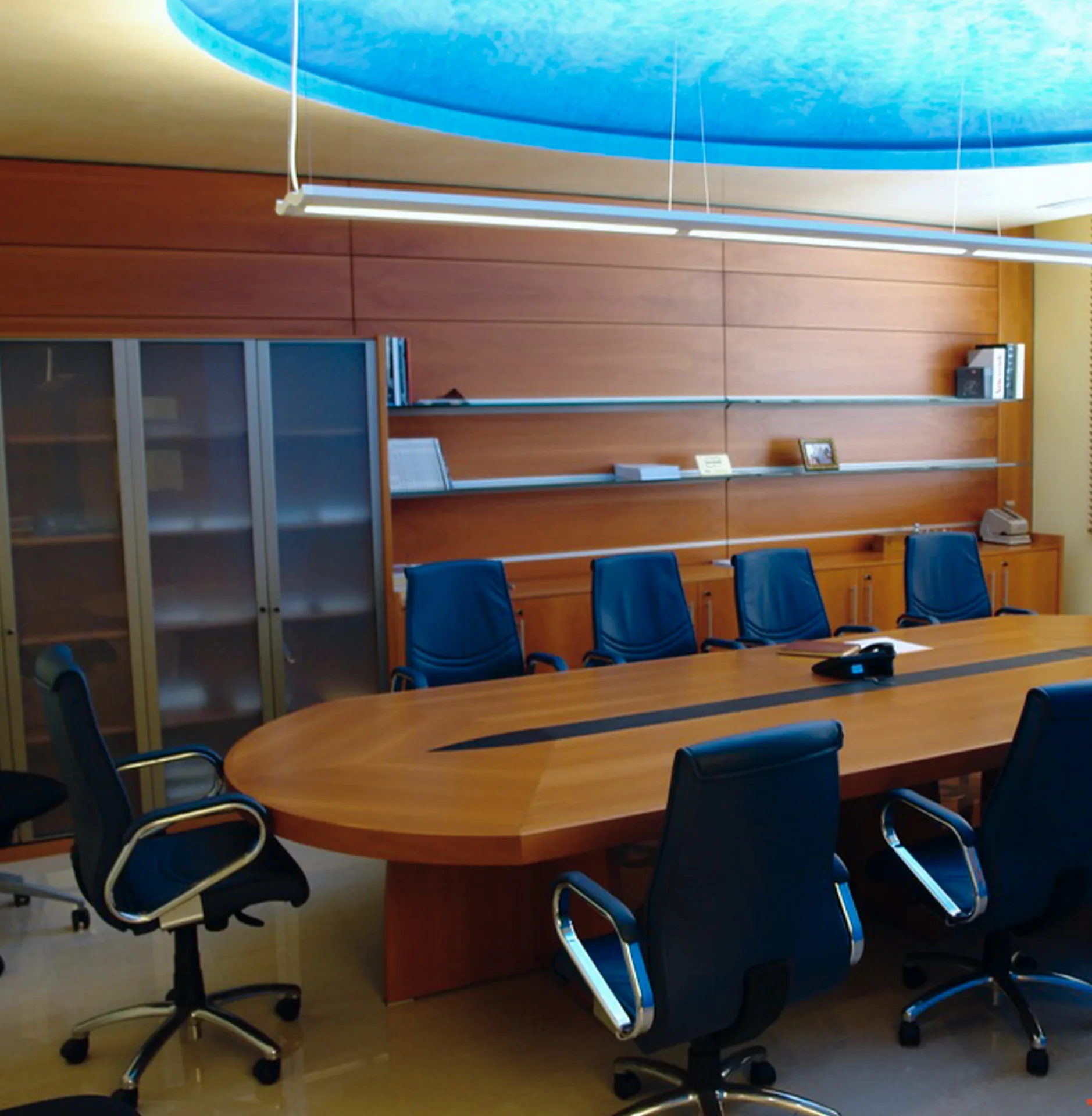 Sala de juntas con mesa oval en cerezo y plafón circular retroiluminado