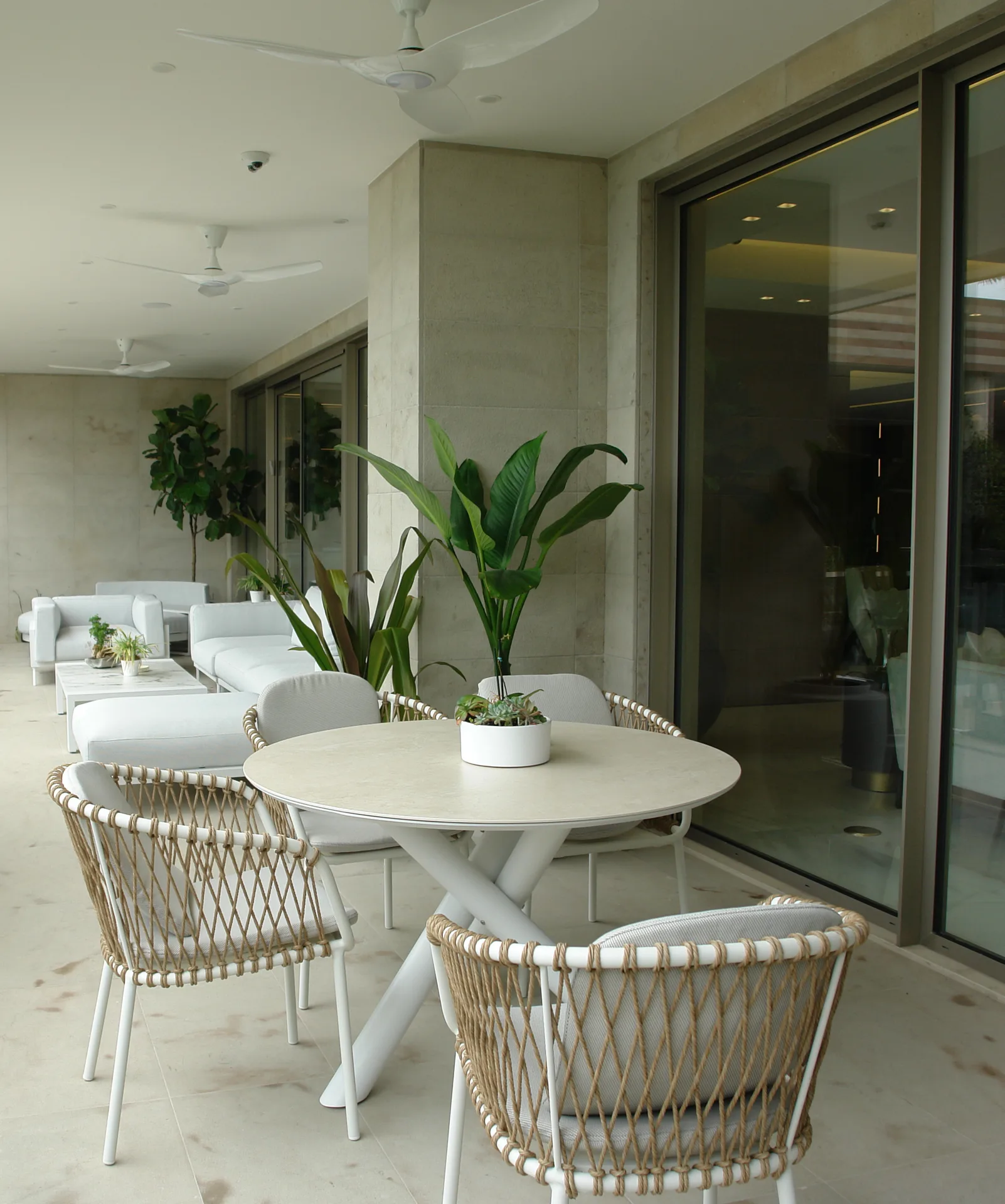 Terraza con mesa redonda, butacas trenzadas y vegetación
