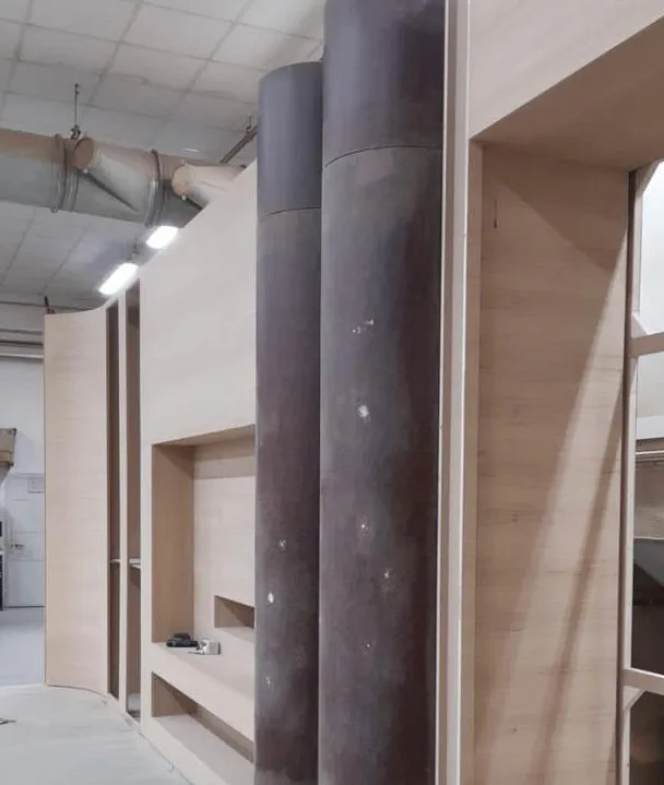 Boiserie en madera clara y columnas revestidas en metal, en taller