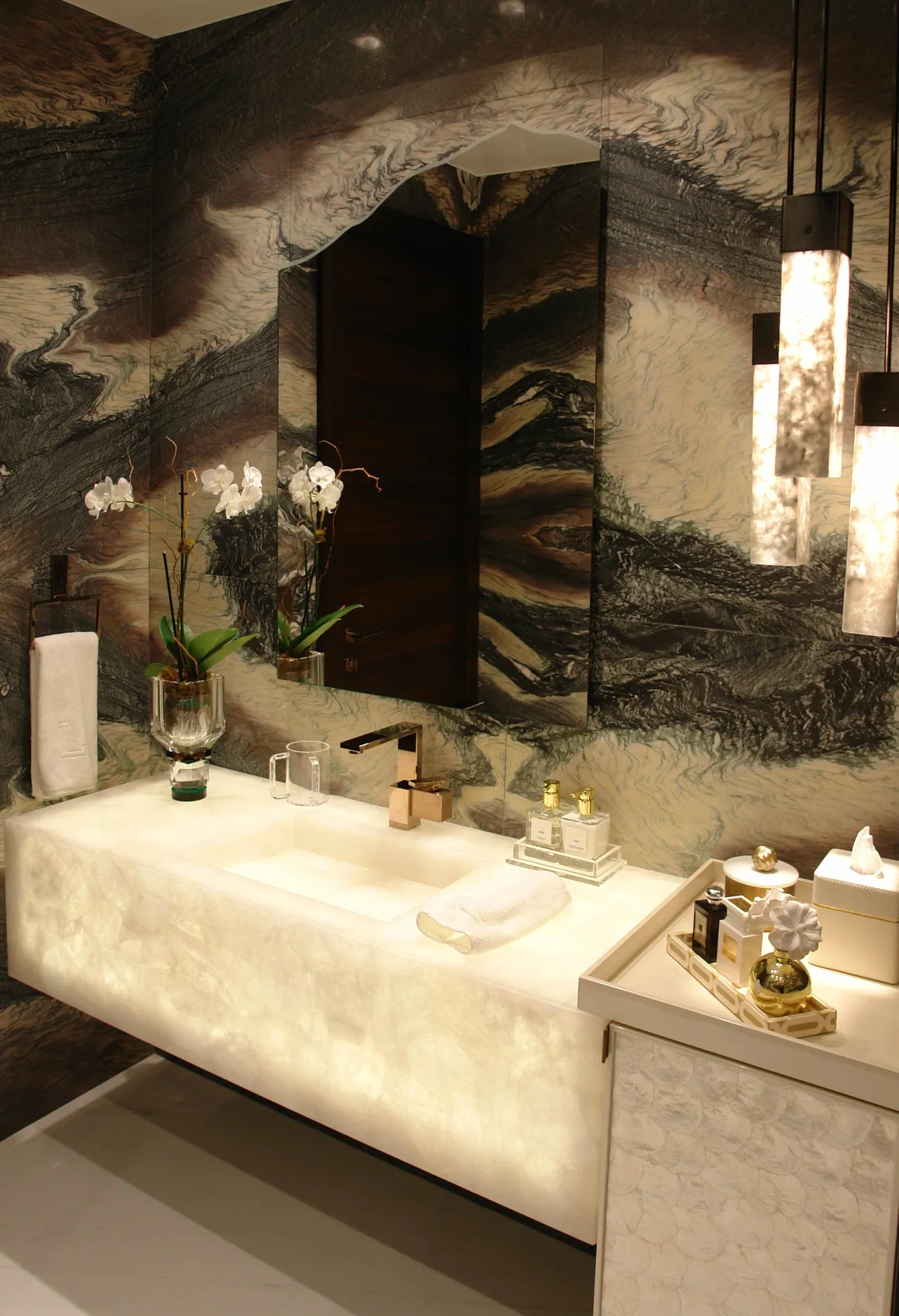 Baño revestido en mármol de vetas naturales con lavabo en ónix retroiluminado