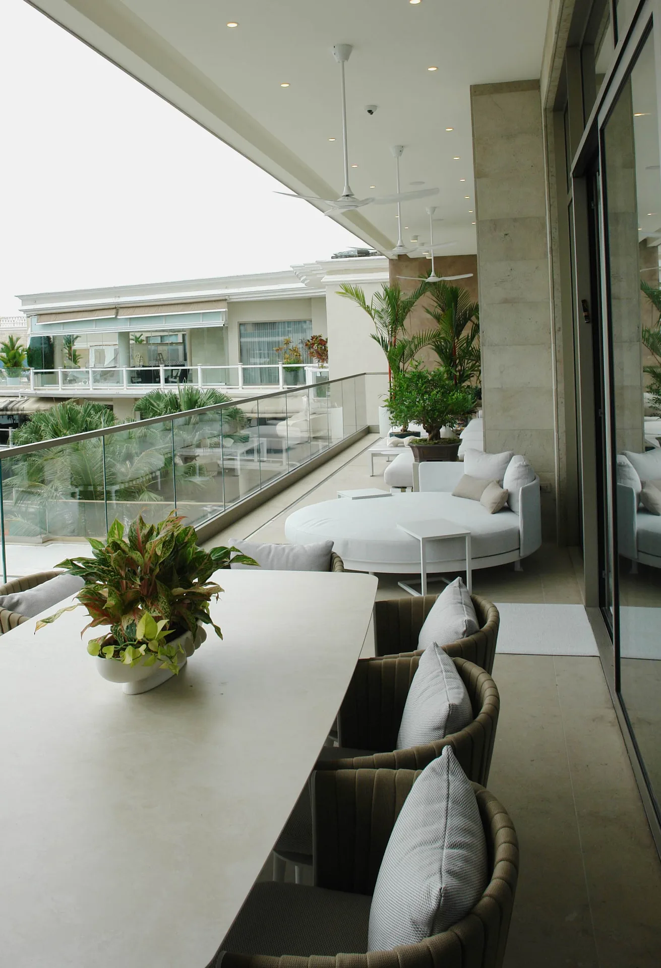 Terraza con salón exterior, vegetación y barandilla de vidrio
