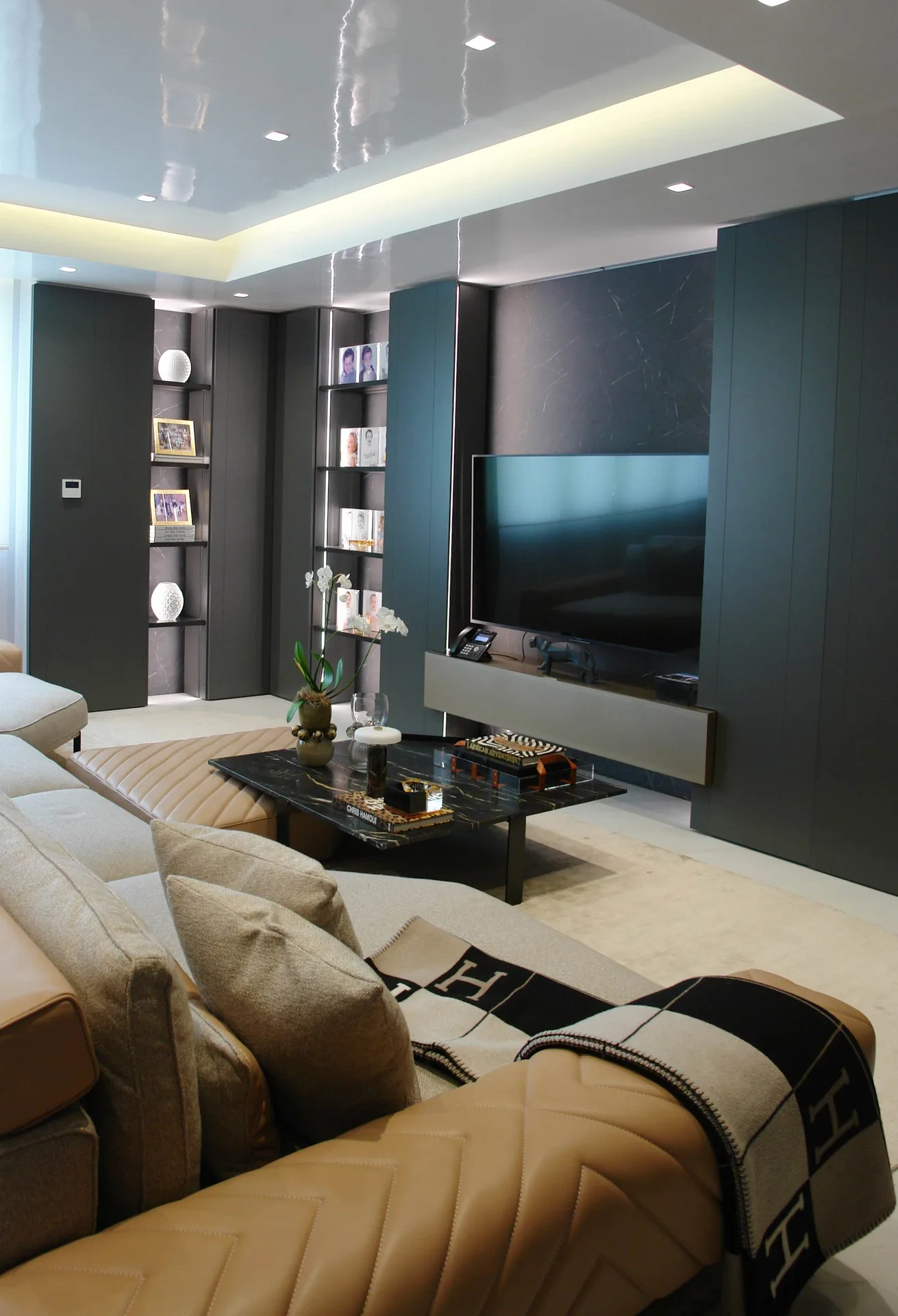 Sala de estar con panelado oscuro, sofá modular e iluminación perimetral