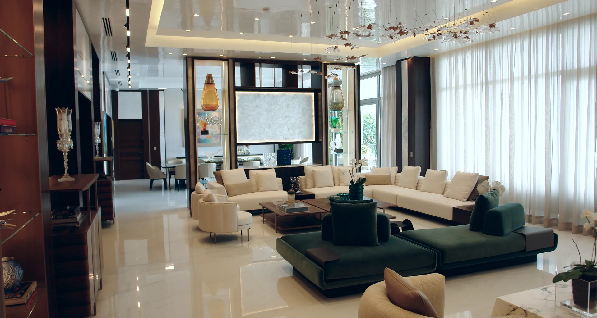 Gran salón con sofás blancos, chaise longue en terciopelo verde y lámpara escultórica de cristal