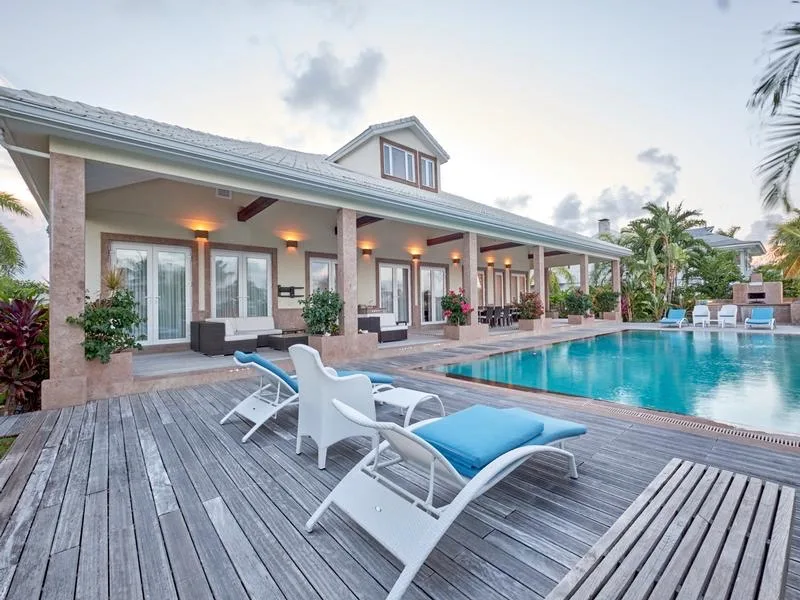 Villa con porche cubierto, terraza de madera y piscina al atardecer
