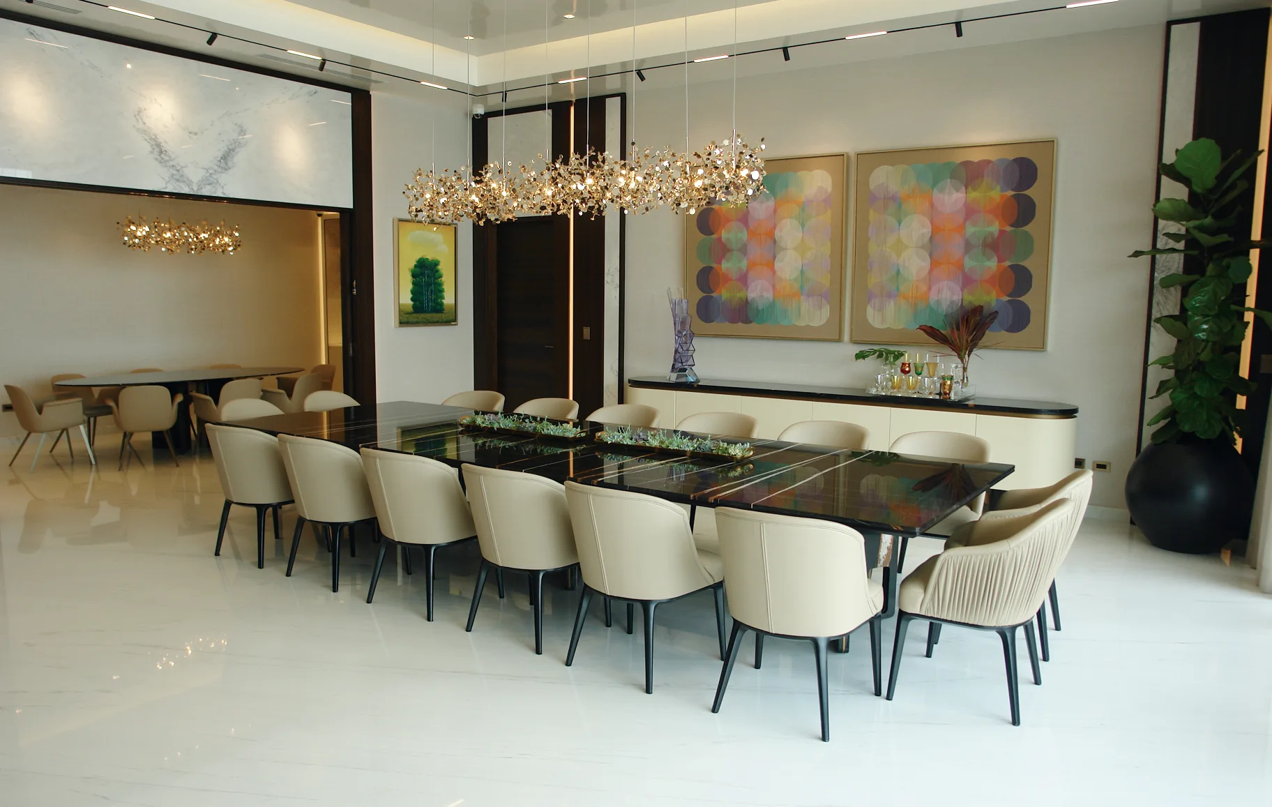 Comedor de una villa privada con lámparas escultóricas de latón, mesa en mármol negro y obras de arte